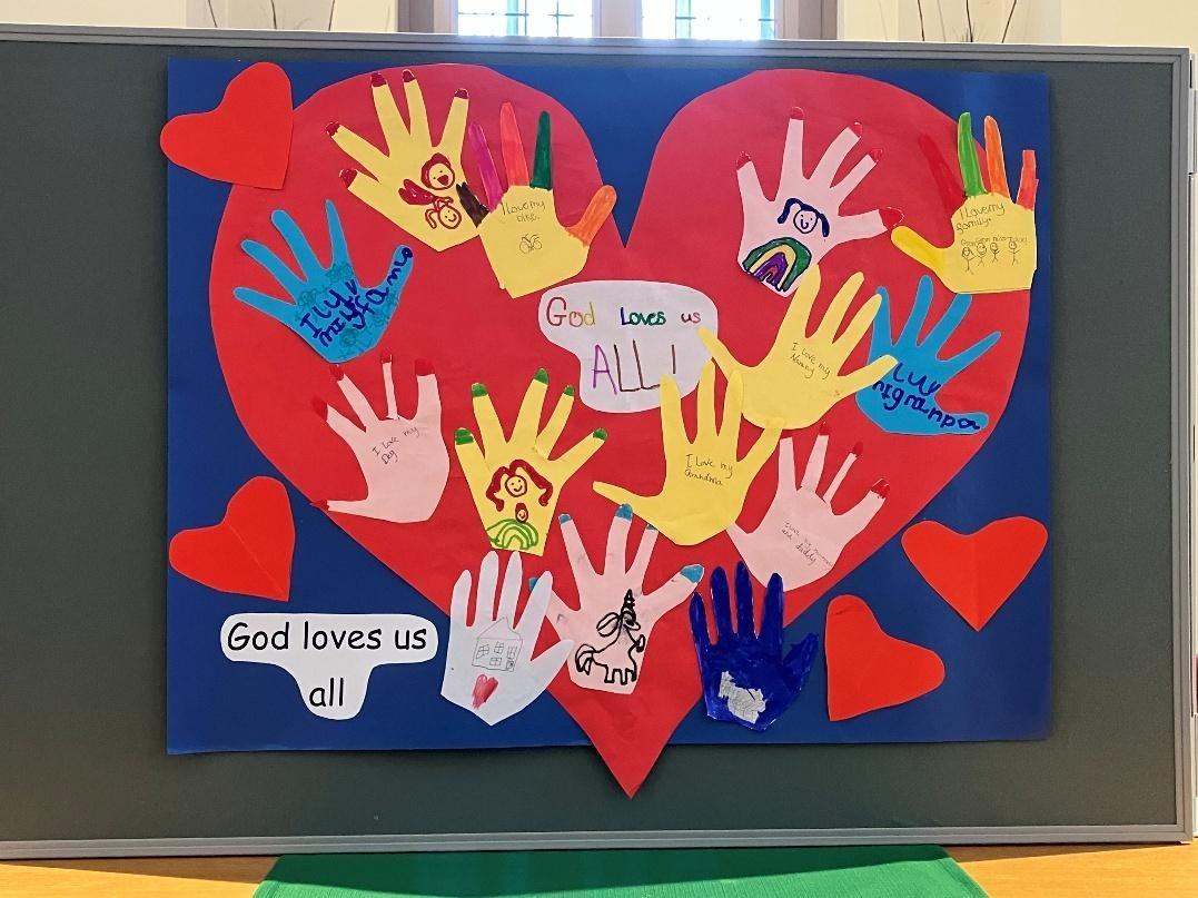 A display of children's handprints on a big red paper heart